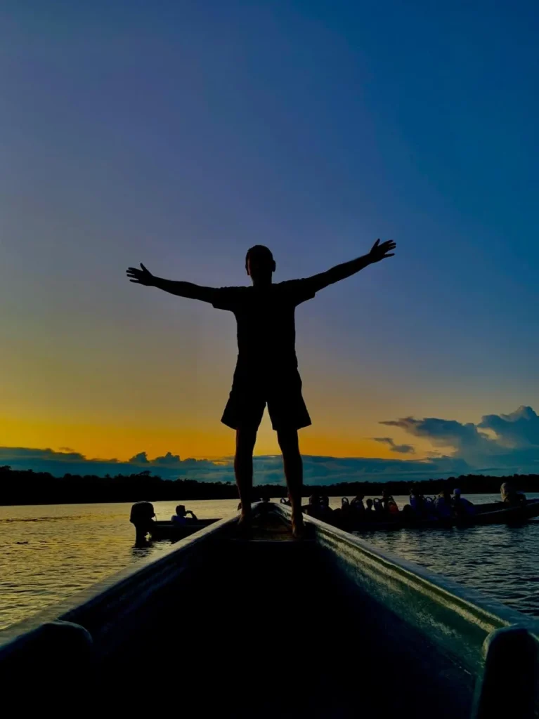 Traveller standing on a canoe at sunset in the Ecuadorian Amazon